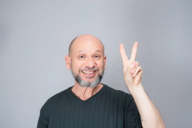 Portrait of mature man standing on white background. Bald bearded man making gestures. Formal style.