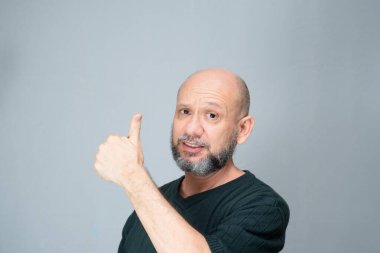 Portrait of mature man standing on white background. Bald bearded man making gestures. Formal style.