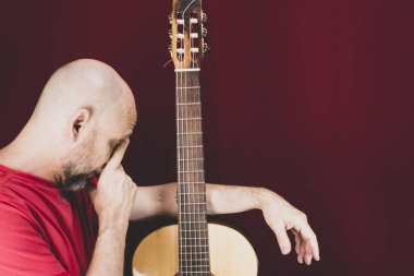 String musical instrument. Mature charismatic male guitarist. guy with beard holds guitar. bearded man in a red shirt. Music performer of music.