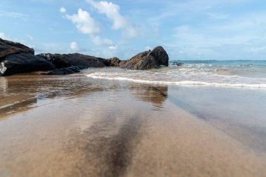 A wave breaks about a rock during a curtain on the sea. Farol da Barra beach, Salvador, Brazil.