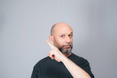 Portrait of mature man standing on white background. Bald bearded man making gestures. Formal style.