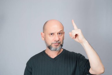Portrait of mature man standing on white background. Bald bearded man making gestures. Formal style.