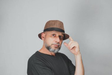 Portrait of mature man standing on white background. Bald bearded man in a brown hat. Formal style.