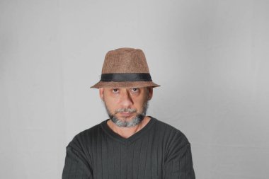 Portrait of mature man standing on white background. Bald bearded man in a brown hat. Formal style.