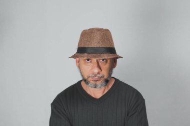 Portrait of mature man standing on white background. Bald bearded man in a brown hat. Formal style.