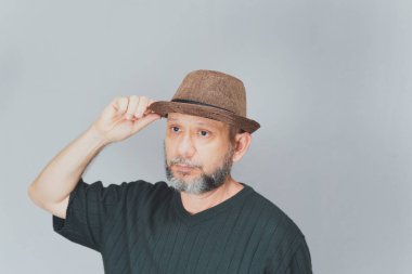 Portrait of mature man standing on white background. Bald bearded man in a brown hat. Formal style.