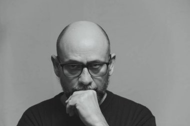 Black and white portrait of mature serious man. Wearing prescription glasses and looking at the camera. Formal style.