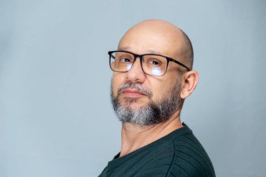 Portrait of mature man standing on light background. Bearded bald man in glasses. Formal style.
