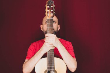String musical instrument. Mature charismatic male guitarist. guy with beard holds guitar. bearded man in a red shirt. Music performer of music.