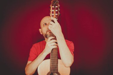String musical instrument. Mature charismatic male guitarist. guy with beard holds guitar. bearded man in a red shirt. Music performer of music.