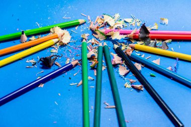 Mavi arka planda izole edilmiş renkli kalemler. Kapatın. Keskinleştirilmiş kalem artıkları.