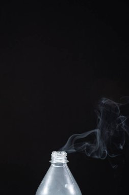 Plastik bir şişeden siyah bir arka planda duman çıkıyor. Cadılar Bayramı için arka plan. Doku sisi. Tasarım elemanı. Aromaterapi kavramı.