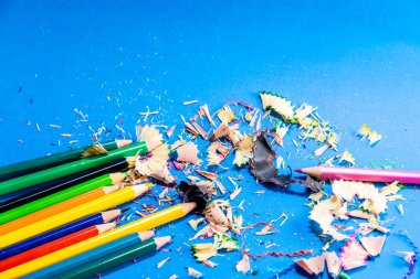 Mavi arka planda izole edilmiş renkli kalemler. Kapatın. Keskinleştirilmiş kalem artıkları.