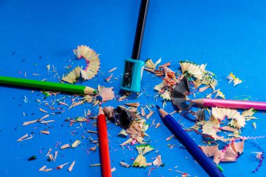 Mavi arka planda izole edilmiş renkli kalemler. Kapatın. Keskinleştirilmiş kalem artıkları.