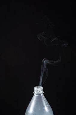 Plastik bir şişeden siyah bir arka planda duman çıkıyor. Cadılar Bayramı için arka plan. Doku sisi. Tasarım elemanı. Aromaterapi kavramı.