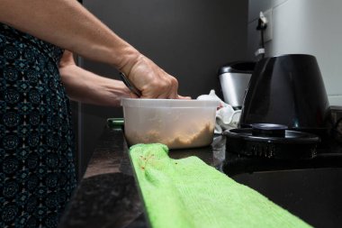 Mutfakta çeşitli malzemelerle cheesecake hazırlayan genç bir kadın. Aile gastronomisi. Salvador, Bahia, Brezilya