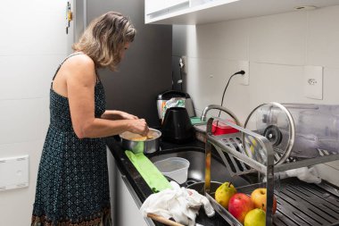 Mutfakta çeşitli malzemelerle cheesecake hazırlayan genç bir kadın. Aile gastronomisi. Salvador, Bahia, Brezilya