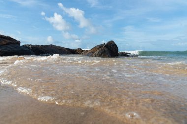 A wave breaks about a rock during a curtain on the sea. Farol da Barra beach, Salvador, Brazil.