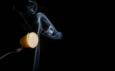 Çatalla şişlenmiş tatlı bir patates aşağıdan beyaz duman alıyor. Kapat.. 