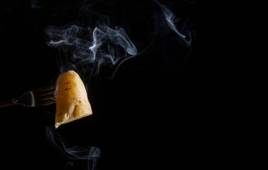 Çatalla şişlenmiş tatlı bir patates aşağıdan beyaz duman alıyor. Kapat.. 
