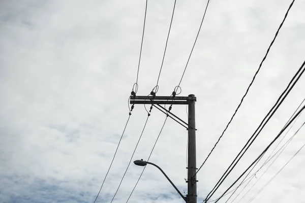 Utility pole with electric wires against blue cloudy sky. Salvador, Bahia, Brazil.