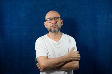 Portrait of a bearded bald man against blue background.