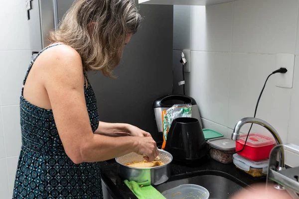 Young woman preparing cheesecake in the kitchen with various ingredients. Family gastronomy. Salvador, Bahia, Brazil