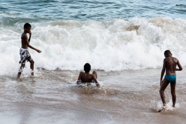 Salvador, Bahia, Brezilya - 1 Nisan 2018: Brezilya 'nın Salvador kentindeki Farol plajında üç genç atlama oyunu oynuyor. Bulutlu ve güzel bir gün.