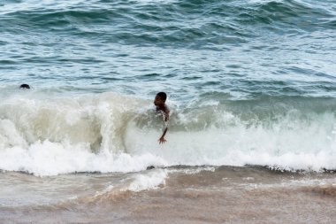 Salvador, Bahia, Brezilya - 1 Nisan 2018: Brezilya 'nın Salvador kentindeki Farol plajında üç genç atlama oyunu oynuyor. Bulutlu ve güzel bir gün.
