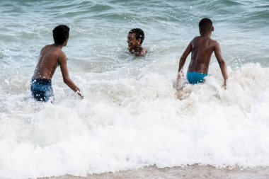 Salvador, Bahia, Brezilya - 1 Nisan 2018: Brezilya 'nın Salvador kentindeki Farol plajında üç genç atlama oyunu oynuyor. Bulutlu ve güzel bir gün.