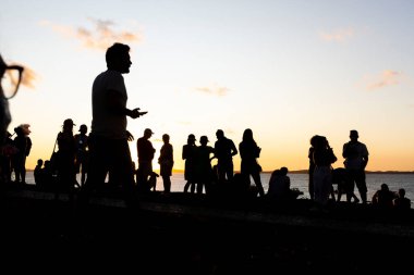 Turistlerin silueti dramatik turuncu günbatımının tadını çıkarıyor. Güzel bir öğleden sonra. Salvador, Brezilya.