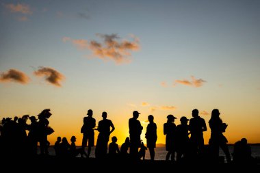 Turistlerin silueti dramatik turuncu günbatımının tadını çıkarıyor. Güzel bir öğleden sonra. Salvador, Brezilya.