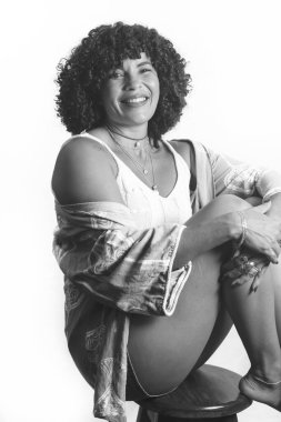 Kıvırcık saçlı bir kadının siyah beyaz portresi. Güzel ve arka planda gülümsüyor. Olgun bir kadın. Özgüven kavramı.