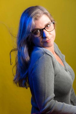 Sarı arka planda gözlük takan bir model portresi. Bardakları manipüle ediyor. Sakin kadın..