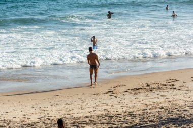 Salvador, Bahia, Brezilya - 22 Ekim 2022: Bir bahar günü Brezilya 'nın Salvador kentindeki Farol da Barra plajına insanlar giriyor.