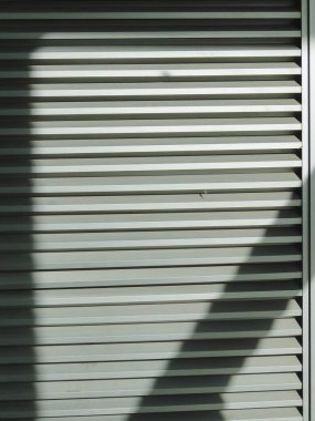 Güneşin gölgesi, paslanmaz çelik arka planda, ağaçların arasından parlıyor..