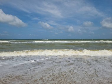 Koyu mavi okyanus dalgası ve temiz kumsalda mavi gökyüzü.