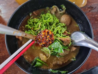 Erişte için baharat. Adamın eli kaşıkla acı biber topluyor ve eriştenin içine koyuyordu..