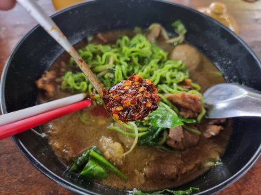 Erişte için baharat. Adamın eli kaşıkla acı biber topluyor ve eriştenin içine koyuyordu..