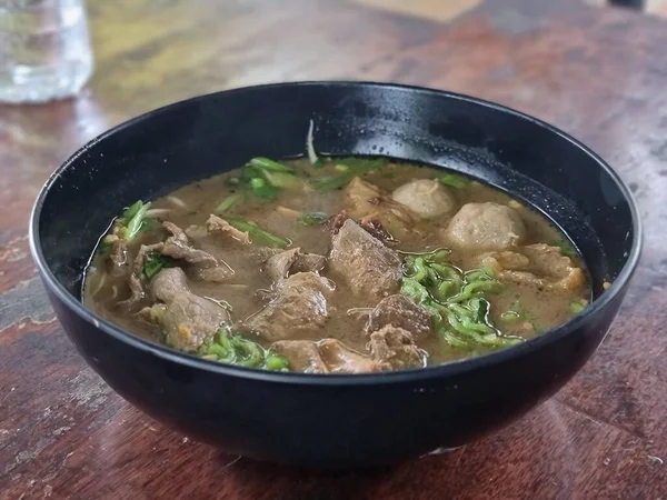 Kalın Çorbada Güveç Eriştesi. Tayland 'ın güneyindeki bir dükkanda, ahşap masanın üzerinde yeşil erişte.