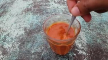 Çay kaşığı sıcak çayı fincanda karıştırıyor. Yavaş çekim.