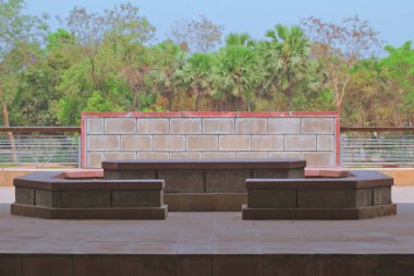 Beton masa ve çatıda harika yeşil manzaralı ve mavi gökyüzü olan koltuklar. Açık hava oturma alanları için modern çatı katı tarzı beton veranda.