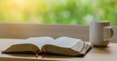 Sabah İncil 'i ve kahveyi yeşil doğa arka bahçeli bir ahşap masada.