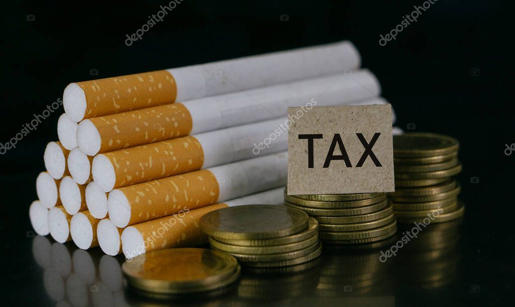 Cigarrillos y palabra TAX sobre fondo negro.Cigarrillos y concepto TAX