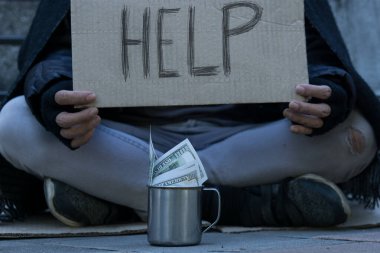 Dilenci, evsiz yetişkin bir adam sokakta yardım almak için oturuyor. İnsanların ilgisizliği. Sosyal meseleler. Mukavvaya yazmama yardım et..