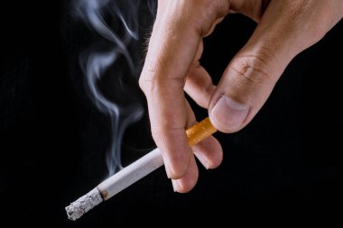 Cigarette.Closeup hand of man holding a cigarette.tobacco cigarette butt on the floor.World no tobacco day.Sign of stop smoking for no smoking day.