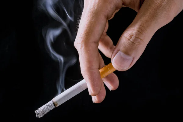 Cigarette.Closeup hand of man holding a cigarette.tobacco cigarette butt on the floor.World no tobacco day.Sign of stop smoking for no smoking day.