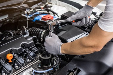Mechanic man working on the engine of the car in the garage.Car service and maintenance,Repair service.Checks car engine under the hood