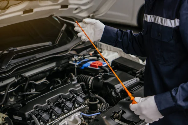 Mechanic man checking car engine oil of the car in the garage.Car service and maintenance,Repair service.Checks car engine under the hood