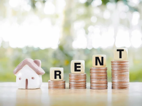 Wooden blocks with the word RENT on stack of coins. The concept of house and property for rent. Property sale.